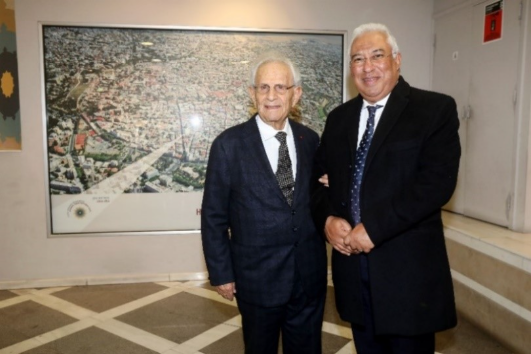 A couple of men standing in front of a large framed picture
Description automatically generated